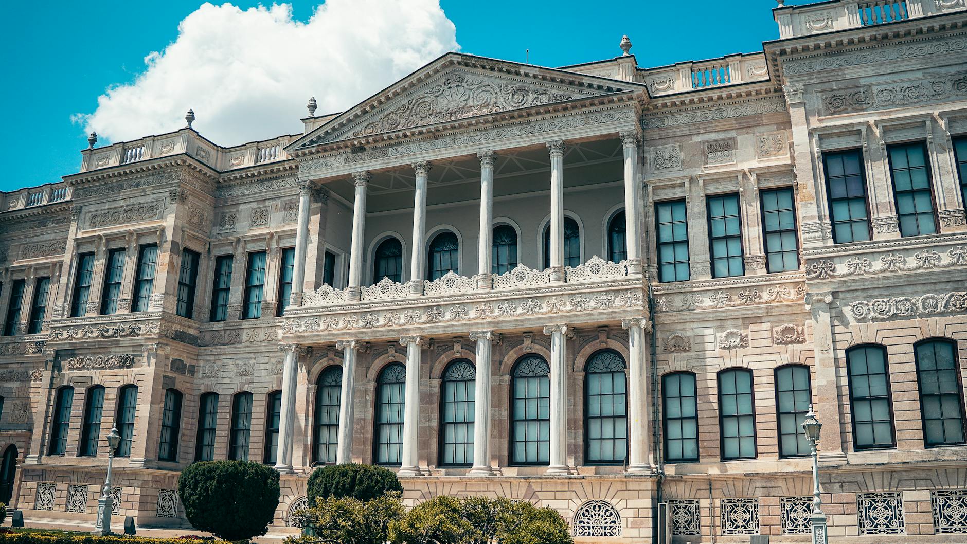 Façade majestueuse du palais impérial de Dolmabahçe sous un ciel nuageux.