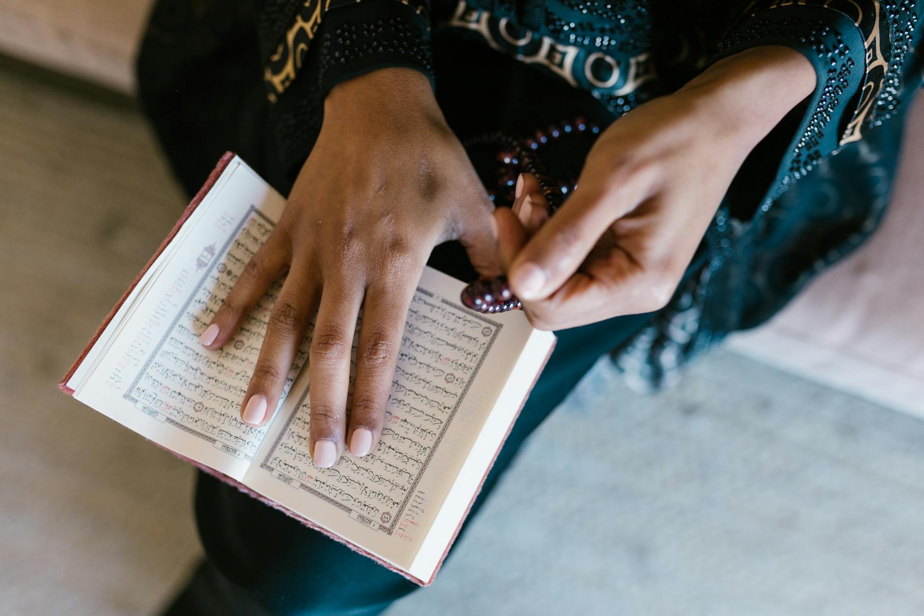 Main posée sur un exemplaire ouvert du Coran avec un chapelet.
