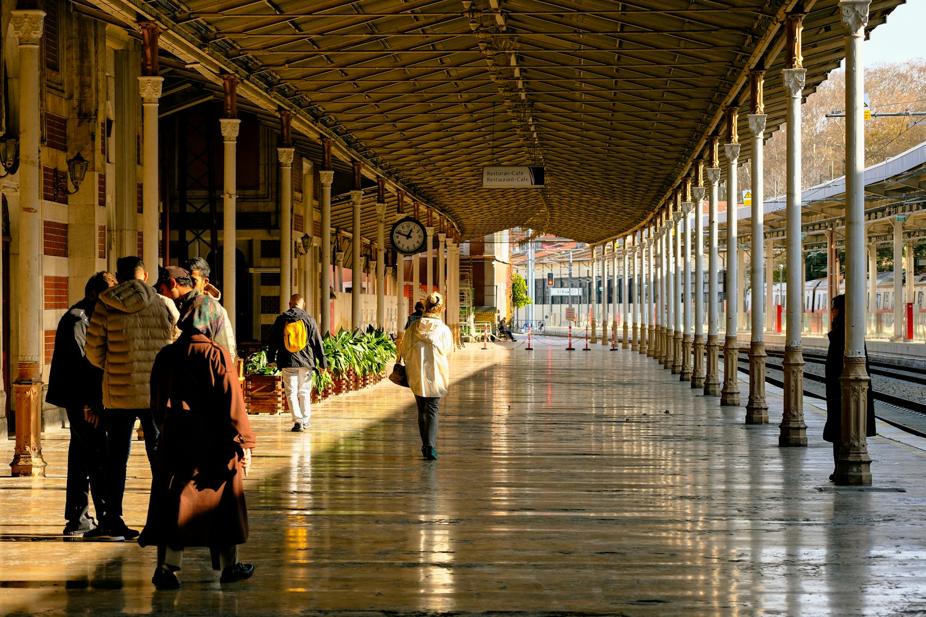 Passagers marchant sur le quai de la gare de Sirkeci sous le soleil.