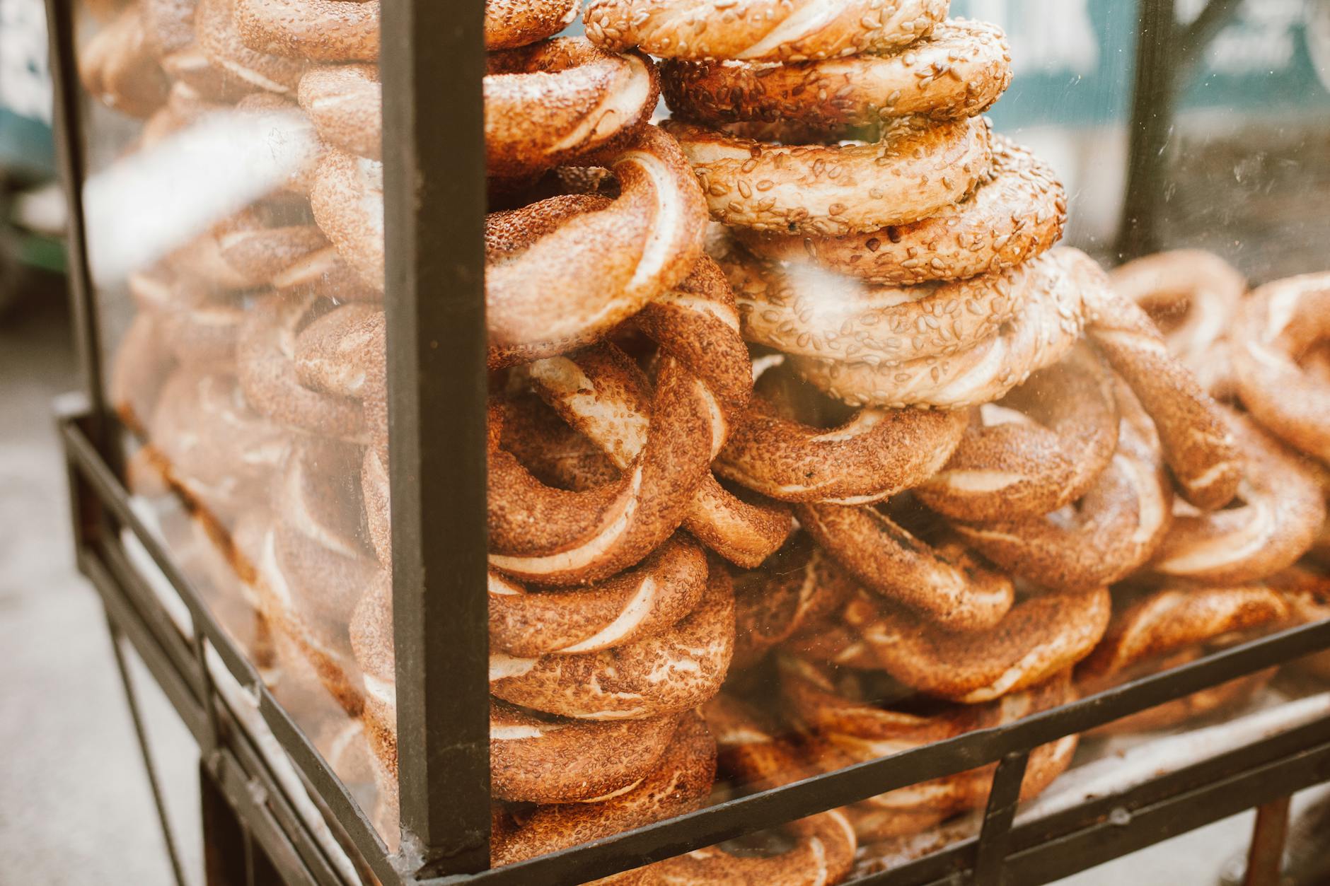 Gros plan sur une pile de simits (bagels turcs) recouverts de graines de sésame, exposés dans une vitrine sur un chariot de rue à Istanbul.