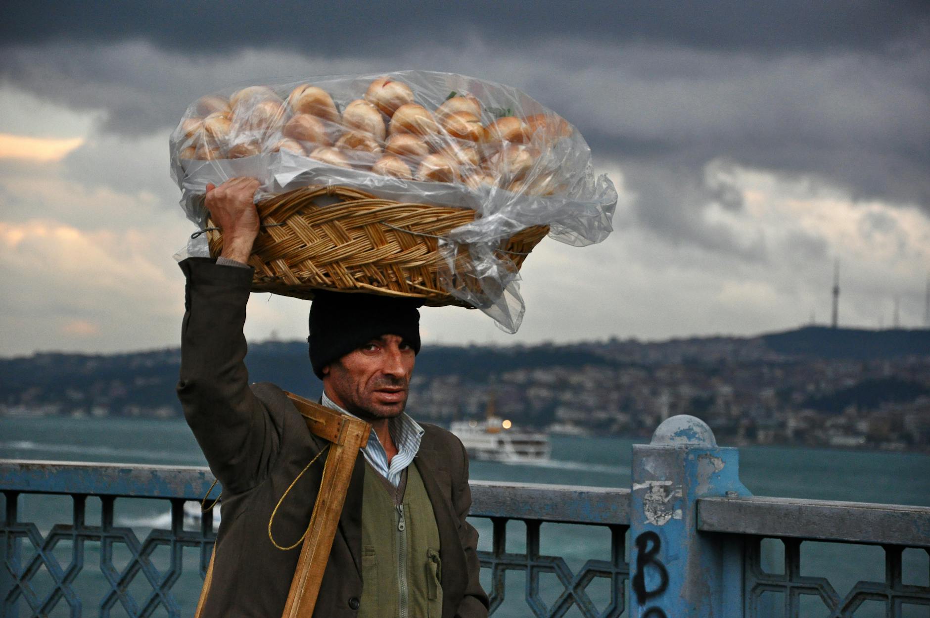 Un vendeur ambulant transporte un panier de pains traditionnels sur sa tête.