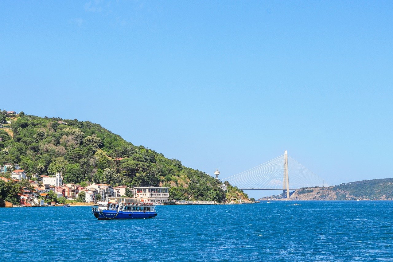 Un bateau bleu navigue sur le Bosphore devant le pont Yavuz Sultan Selim.